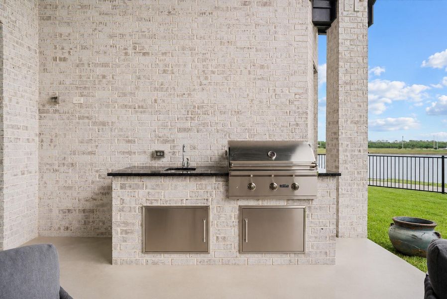 Spacious covered patio with an outdoor kitchen overlooking the water, perfect for relaxing or entertaining year-round.