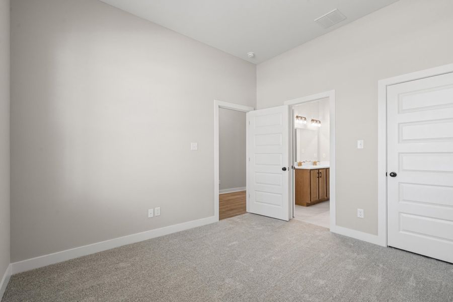 Unfurnished bedroom featuring light carpet and connected bathroom