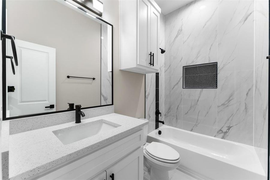 Full bathroom featuring vanity, tiled shower / bath combo, and toilet