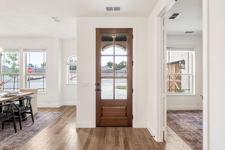 Entryway with wood front door featuring glass panels, hardwood floors, and white walls with dining area visible