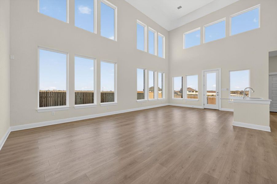 Unfurnished living room featuring light wood-style flooring and a towering ceiling