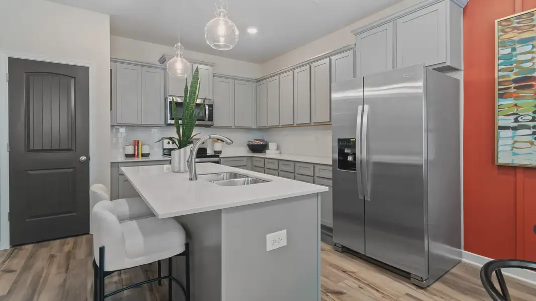 Kitchen with grey cabinetry, quartz countertops, and tile backsplash