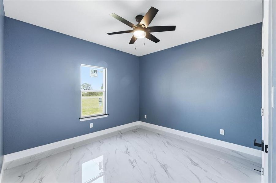 Spare room with marble look tile flooring and ceiling fan