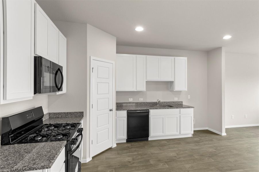 Kitchen featuring black appliances, dark wood-style floors, white cabinetry, recessed lighting, and dark stone counters