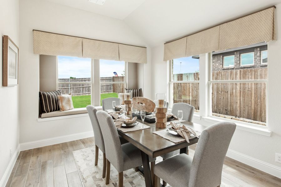 Dining room with dark wood table, gray chairs, window seat, and large windows with backyard views