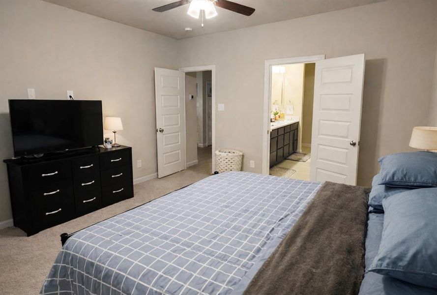 Bedroom with light carpet, a ceiling fan, and ensuite bathroom