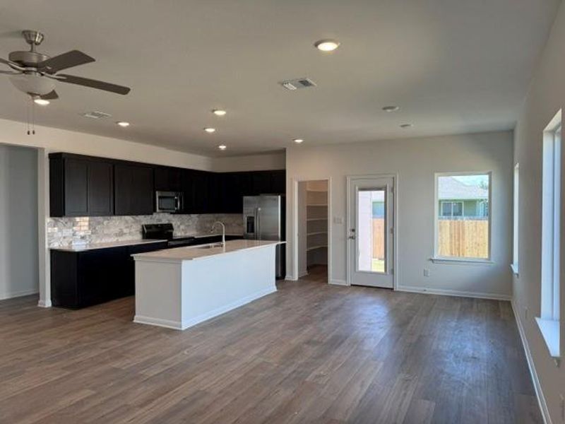 Open-concept kitchen and living area featuring wood-finish flooring, recessed lighting, and a ceiling fan Open-concept kitchen and living area featuring wood-finish flooring, recessed lighting, and a ceiling fan