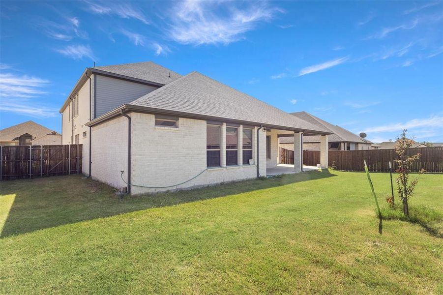 Back of house featuring a patio, a shingled roof, brick siding, and a fenced backyard