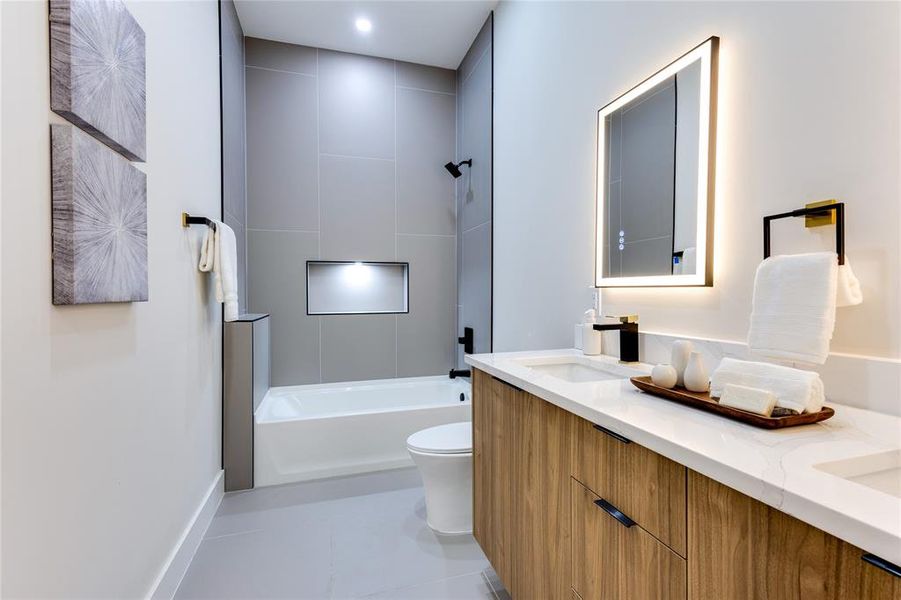 Full bathroom with dual bowl vanity, tiled shower / bath combo, tile patterned floors, and toilet