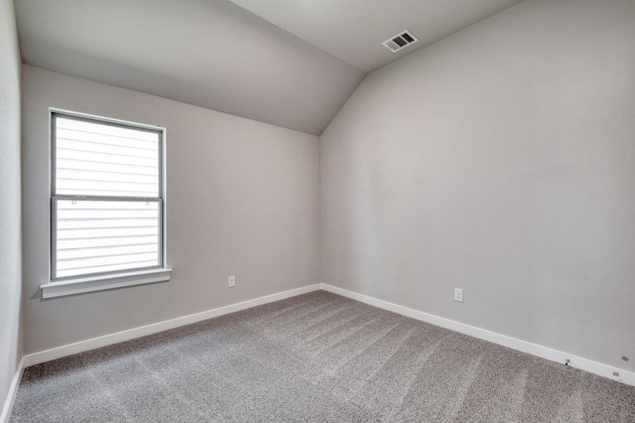 An airy bedroom with a sloped ceiling and well-lit interior, providing a serene retreat. An airy bedroom with a sloped ceiling and well-lit interior, providing a serene retreat.
