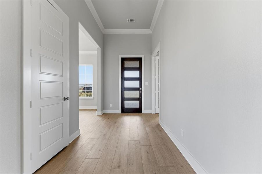 Doorway with crown molding, wood-type flooring, and arched walkways