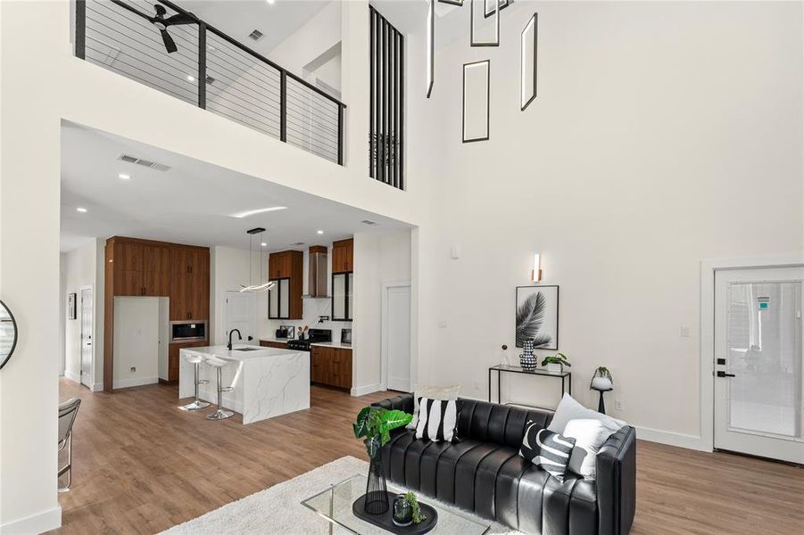 Living room with light wood-type flooring, recessed lighting, and a high ceiling