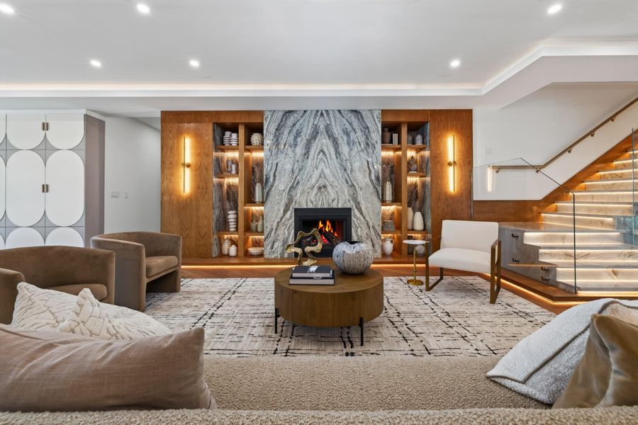 Grand living room anchored by a dramatic fireplace, custom built-ins and warm wood detailing.