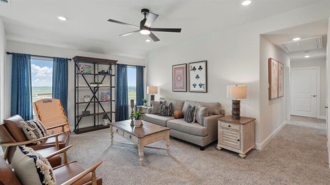 Spacious carpeted room featuring a ceiling fan with integrated lighting, recessed lighting, and two windows with blue drapery