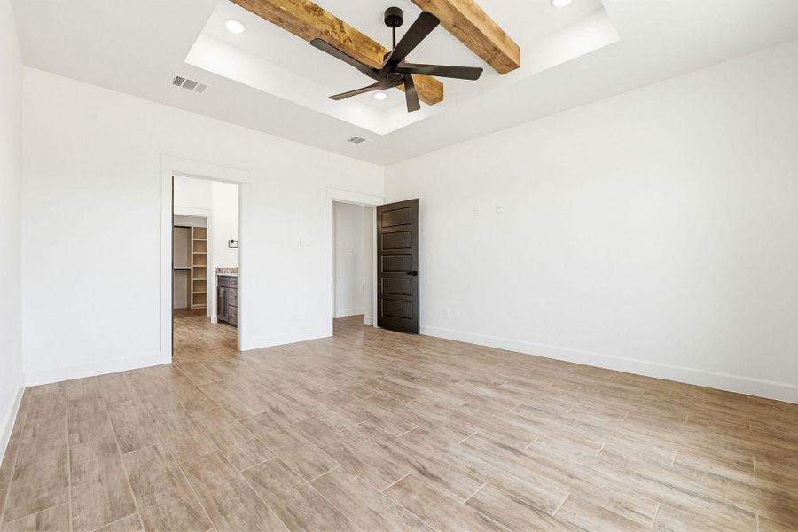 Wood beam ceiling details with a stylish fan elevate this spacious, naturally illuminated room. Wood beam ceiling details with a stylish fan elevate this spacious, naturally illuminated room.