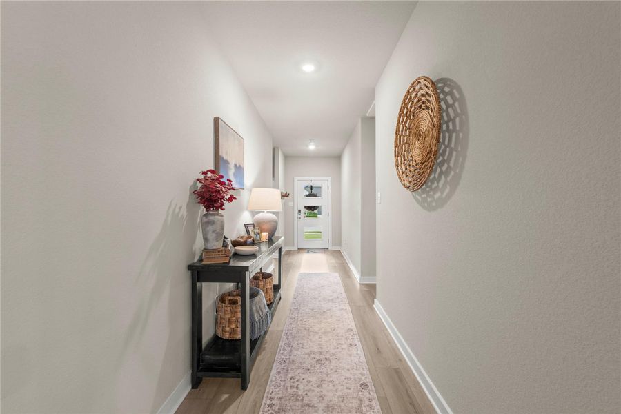Recessed lighting illuminates a long, welcoming hallway leading to an inviting entry door. Recessed lighting illuminates a long, welcoming hallway leading to an inviting entry door.