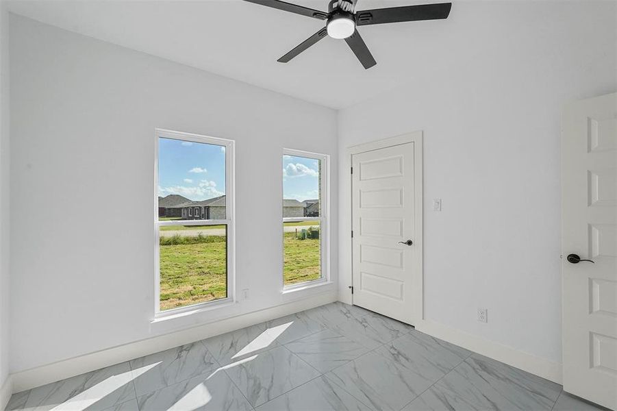 Unfurnished room featuring ceiling fan and plenty of natural light