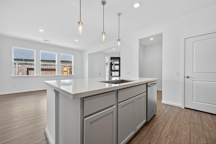 The island is topped with a sleek quartz surface, offering both durability and a polished modern look that elevates the kitchen’s style.