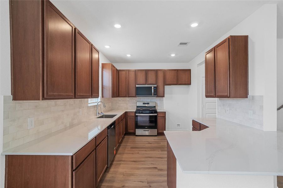 The sprawling U-shaped kitchen layout maximizes efficiency, offering vast counter space and an abundance of rich wood cabinetry for storage. The sprawling U-shaped kitchen layout maximizes efficiency, offering vast counter space and an abundance of rich wood cabinetry for storage.
