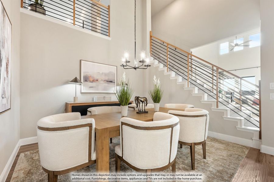 Dining room with wood table, white upholstered chairs, chandelier, and open staircase with two-story ceiling Dining room with wood table, white upholstered chairs, chandelier, and open staircase with two-story ceiling