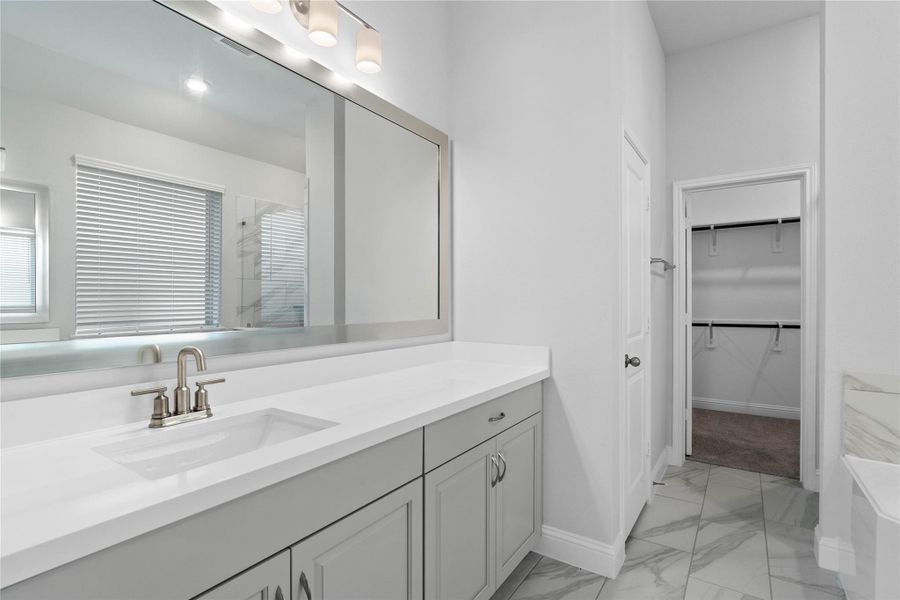 This luxurious primary bathroom serves as a spa-like retreat, featuring a spacious double vanity with sleek light gray cabinetry and crisp white countertops. Modern fixtures, ample lighting, and an expansive mirror create a bright and airy atmosphere. This luxurious primary bathroom serves as a spa-like retreat, featuring a spacious double vanity with sleek light gray cabinetry and crisp white countertops. Modern fixtures, ample lighting, and an expansive mirror create a bright and airy atmosphere.