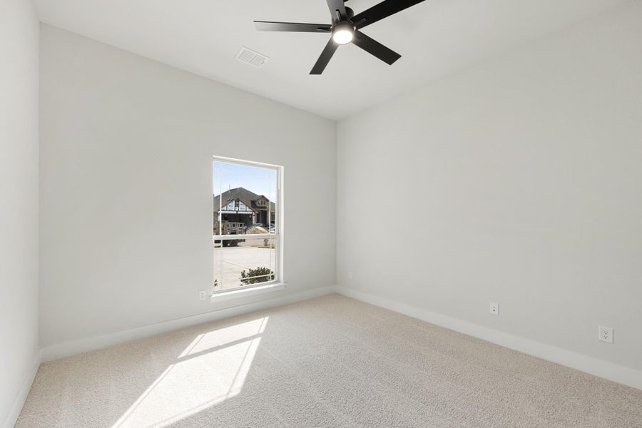 Empty bedroom with carpet flooring, black ceiling fan, and single window with neighborhood view
