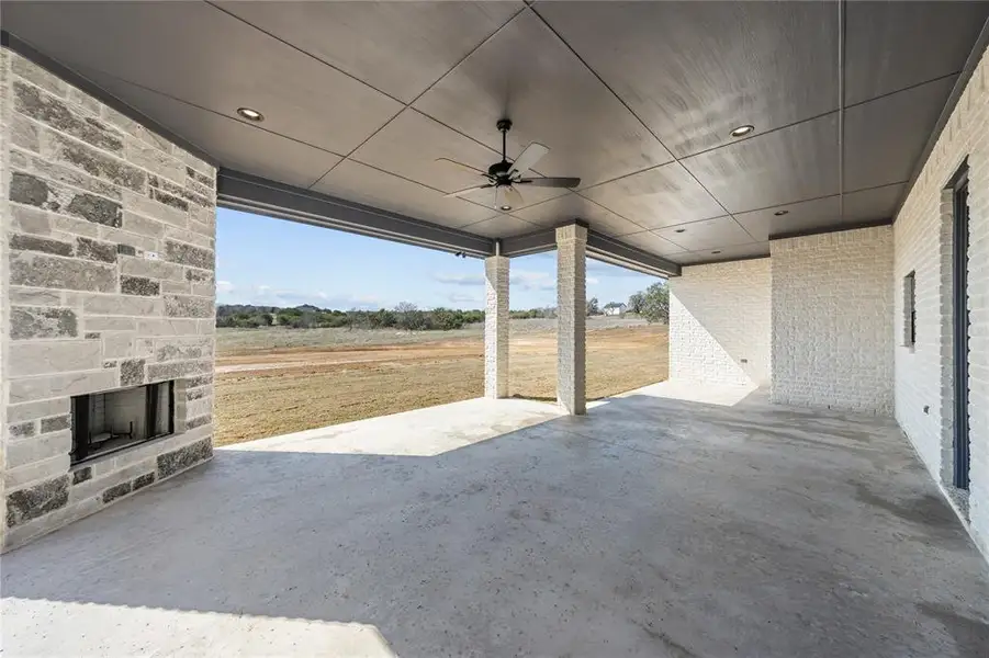 View of patio featuring a ceiling fan and an outdoor stone fireplace