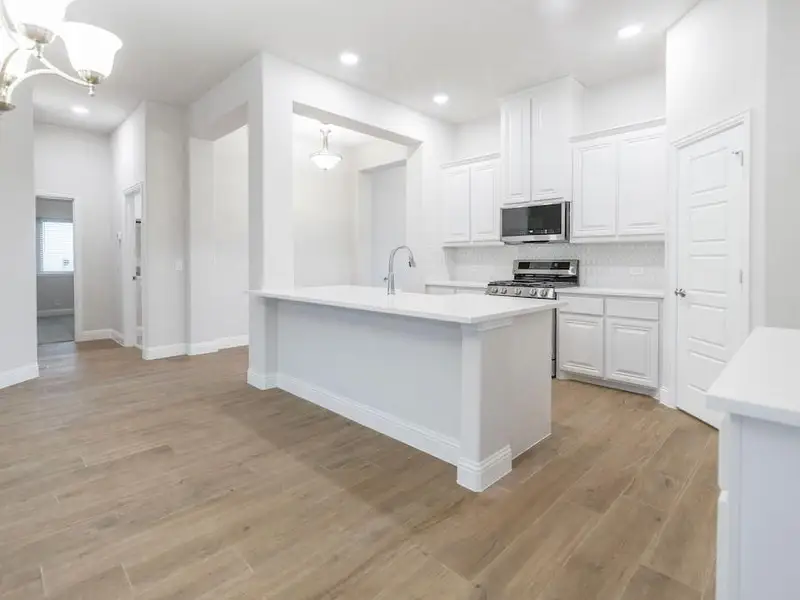 Kitchen with tasteful backsplash, white cabinetry, light hardwood / wood-style flooring, and stainless steel appliances