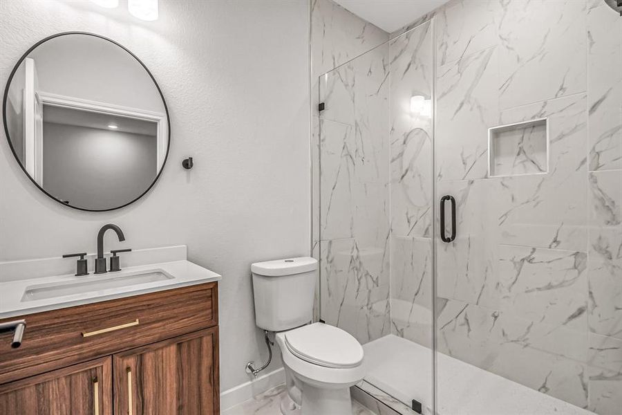 Guest bath on the second floor is stylish with wood vanity and  seamless glass shower enclosure.