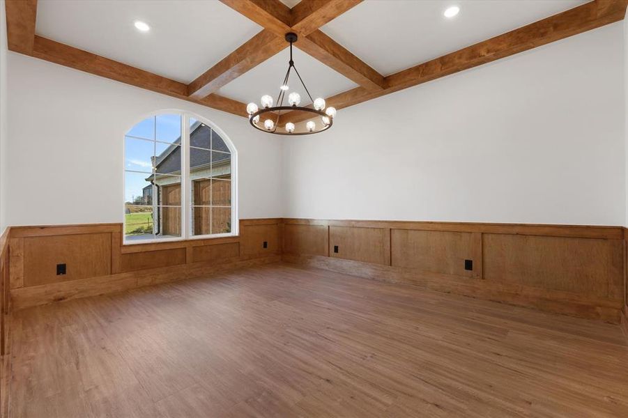 Unfurnished room featuring a wainscoted wall, coffered ceiling, wood finished floors, beam ceiling, and a chandelier