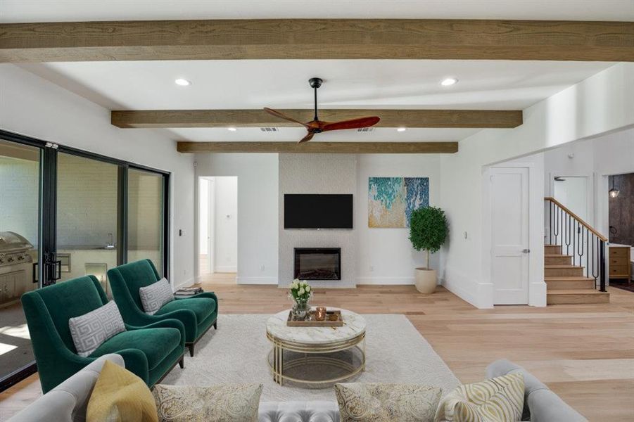 Living room with recessed lighting, light wood-type flooring, a large fireplace, ceiling fan, and beam ceiling