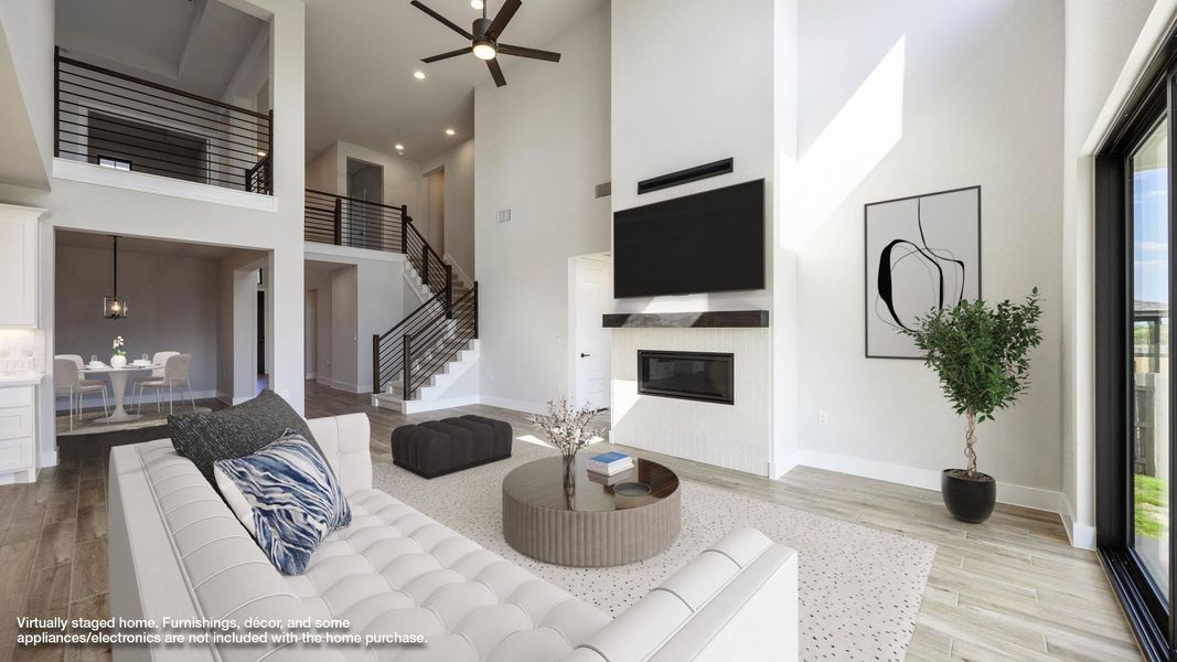 Living room with a towering ceiling, light wood-style flooring, a glass covered fireplace, ceiling fan, and recessed lighting