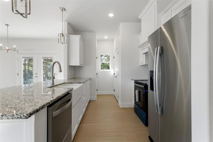 Kitchen with white cabinets, stainless steel appliances, hanging light fixtures, and sink