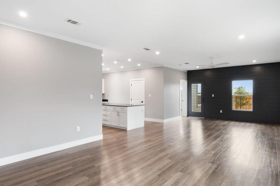Unfurnished living room featuring recessed lighting, light wood-type flooring, ornamental molding, an accent wall, and a ceiling fan