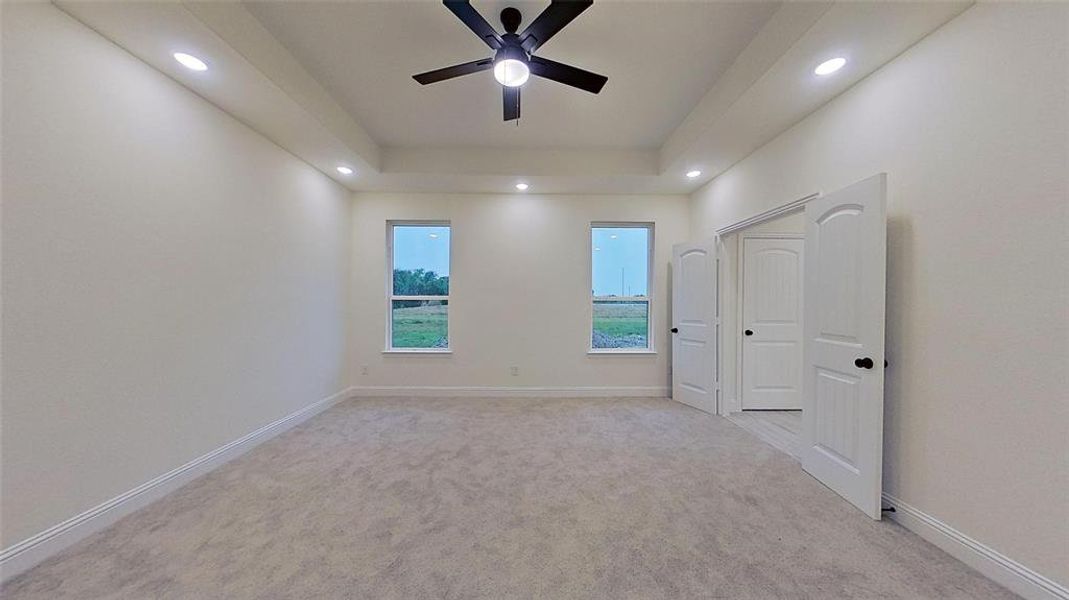 Unfurnished bedroom featuring a tray ceiling, light carpet, ceiling fan, and recessed lighting Unfurnished bedroom featuring a tray ceiling, light carpet, ceiling fan, and recessed lighting