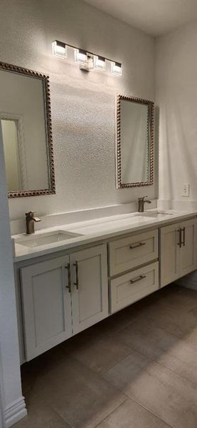 Full bathroom featuring double vanity and dark tile patterned flooring Full bathroom featuring double vanity and dark tile patterned flooring
