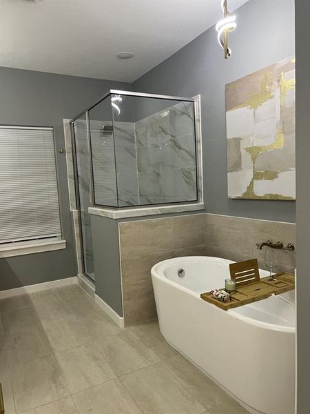 Bathroom with a marble finish shower, a soaking tub, and light tile patterned floors Bathroom with a marble finish shower, a soaking tub, and light tile patterned floors