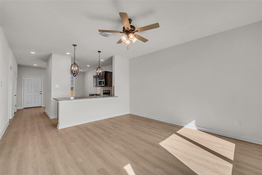 Unfurnished living room with light wood-type flooring, recessed lighting, a chandelier, and ceiling fan