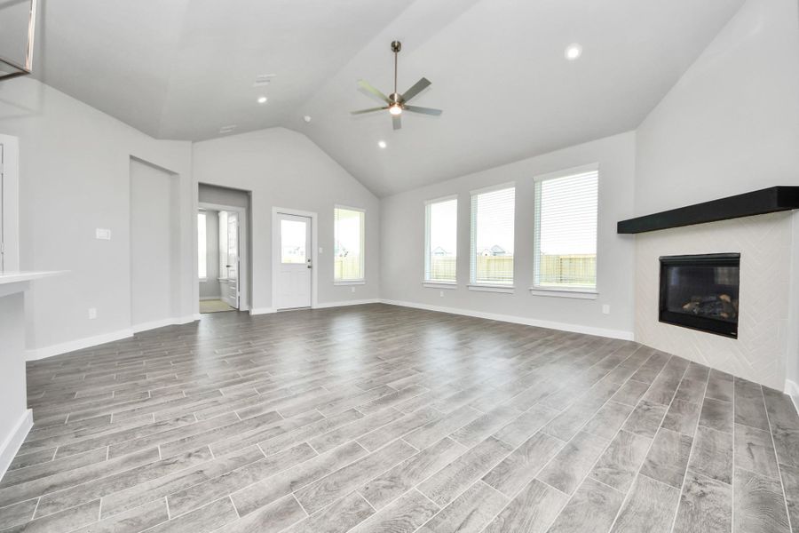 Bring your loved ones and guests together in the inviting living room! Boasting lofty high ceilings, recessed lighting, a stylish ceiling fan, custom paint, stunning flooring, and expansive windows that flood the space with ample natural light all day long. Sample photo of completed home with similar floor plan. Actual colors and selections may vary.