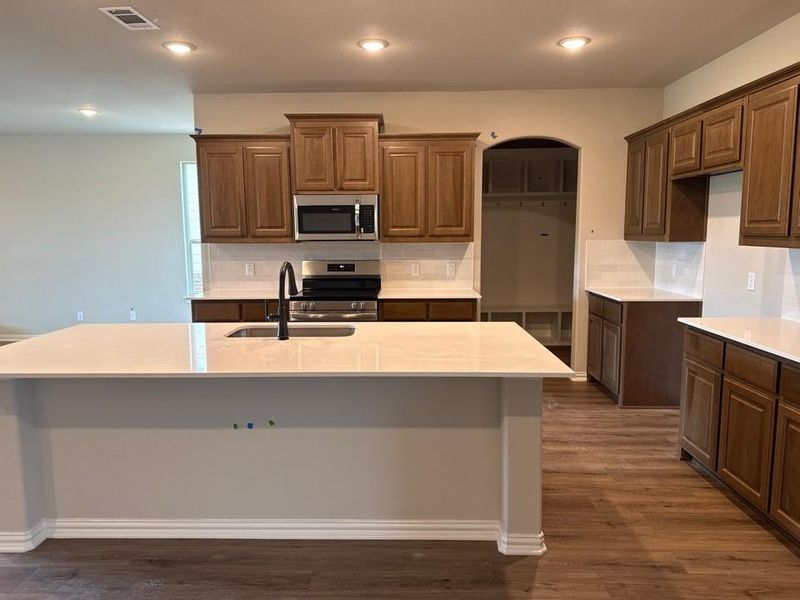Kitchen island featuring a white countertop with an undermount sink and matte black faucet
