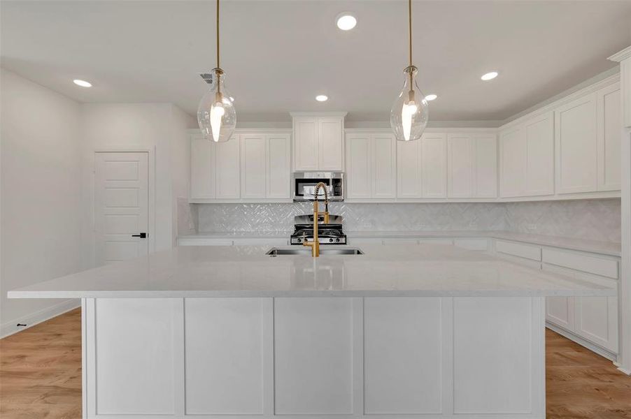 Kitchen with light wood-style flooring, white cabinetry, light stone counters, and stainless steel appliances