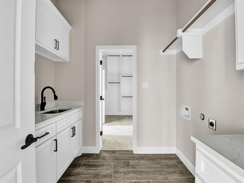 Clothes washing area featuring washer hookup, a sink, wood tiled floor, hookup for an electric dryer, and cabinet space Clothes washing area featuring washer hookup, a sink, wood tiled floor, hookup for an electric dryer, and cabinet space