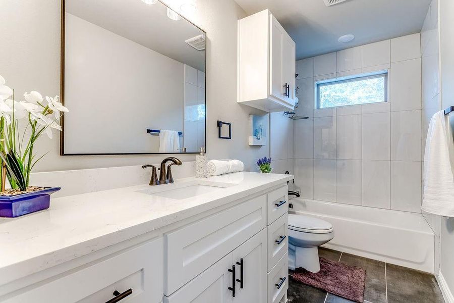 Full bathroom featuring tile patterned flooring, vanity, toilet, and tiled shower / bath