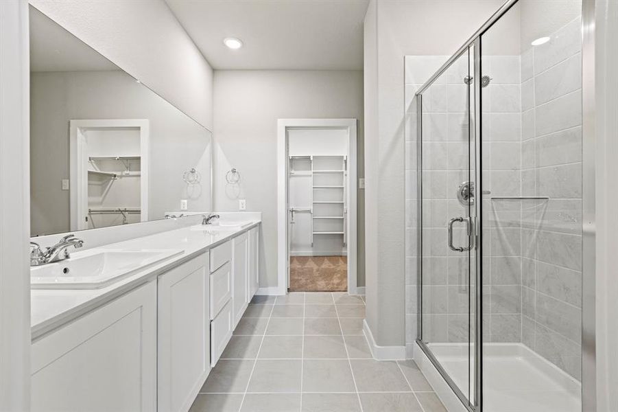 Bathroom featuring double sink, tile floors, oversized vanity, and walk in shower