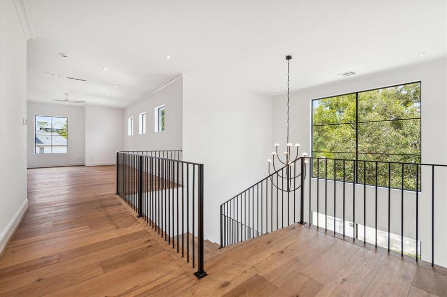 This wide, luxurious staircase elegantly ascends to the second floor, serving as one of two stunning staircases in the home. Illuminated by a Kelly Wearstler alabaster chandelier, the two-story window offers a captivating glimpse of the interior from the street, showcasing the home's exquisite design.