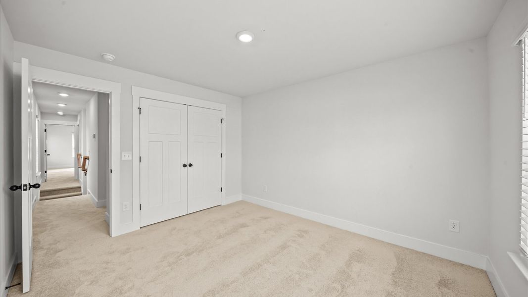 Superior comfort in a secondary bedroom with plush carpet and an oversized walk-in closet