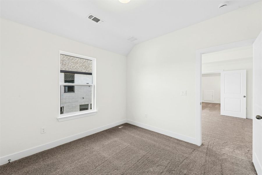 Unfurnished room featuring carpet and lofted ceiling