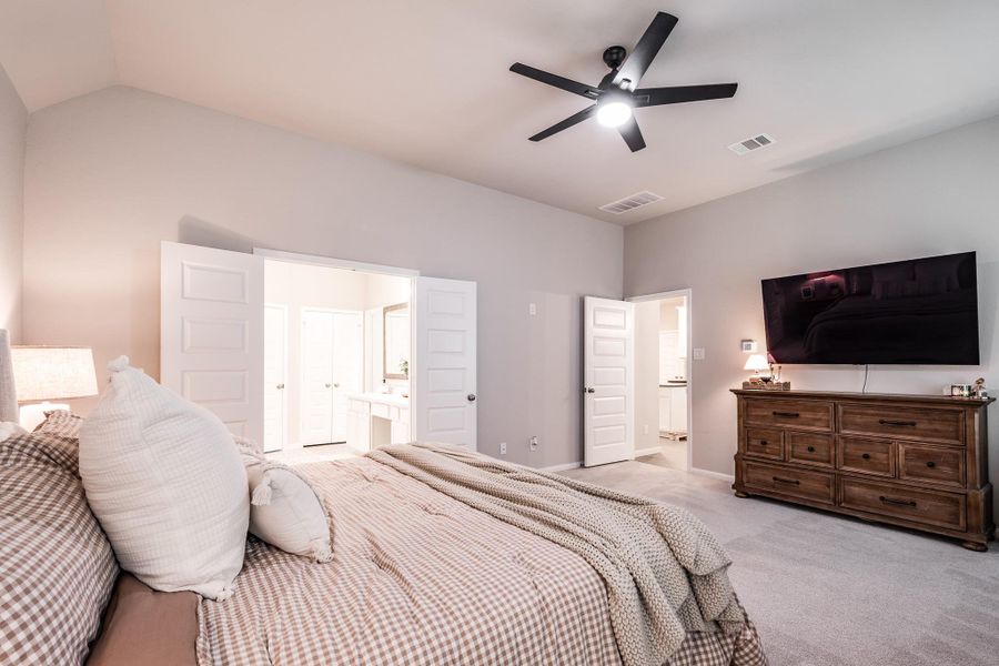 This spacious bedroom features neutral tones, a ceiling fan, and a mounted TV. It includes a cozy bed, ample natural light, and access to an ensuite bathroom. The layout promotes comfort and convenience. This spacious bedroom features neutral tones, a ceiling fan, and a mounted TV. It includes a cozy bed, ample natural light, and access to an ensuite bathroom. The layout promotes comfort and convenience.