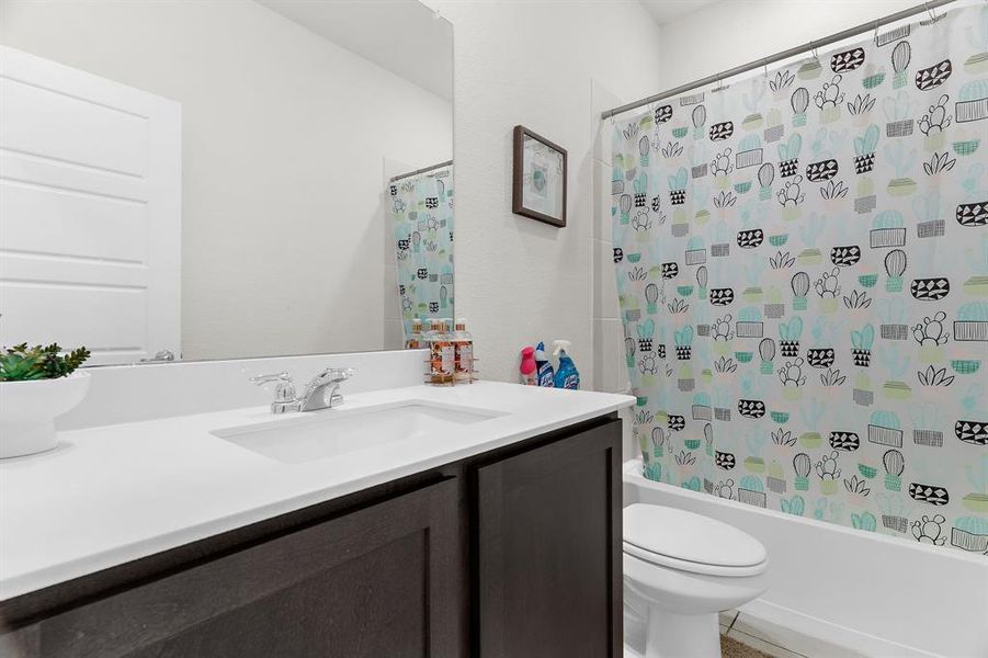 Full bathroom with toilet, vanity, and shower / bath combination with curtain