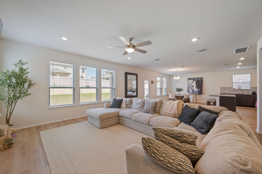 Living area with a ceiling fan, light wood-type flooring, plenty of natural light, and a chandelier